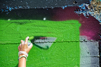 Cropped hand of person spraying paint on wall