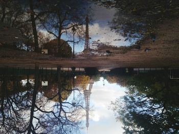 Reflection of trees in puddle against sky