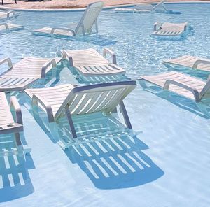 Empty lounge chairs in swimming pool