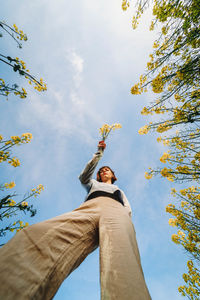 Low angle view of woman against sky with flowers 