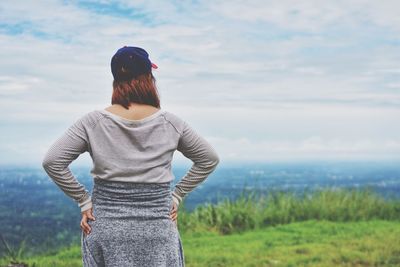 Rear view of woman standing on field against sky