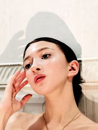 Close-up portrait of young woman against wall
