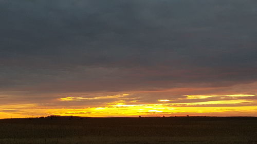 Scenic view of dramatic sky over field during sunset