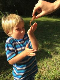 Cropped hand showing snail to boy at park