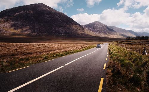 Car driving on empty scenic road trough nature and mountains at connemara national park in ireland 