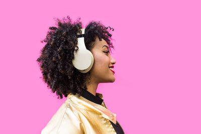 Fashionable young woman with curly hair against pink background