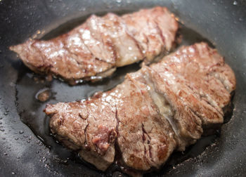 High angle view of meat with oil in cooking pan