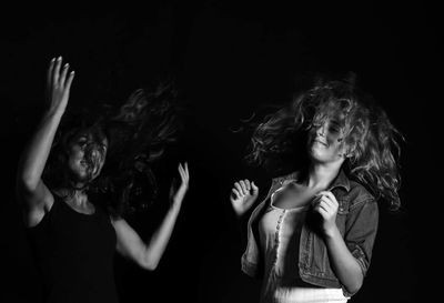 View of girls jumping against black background