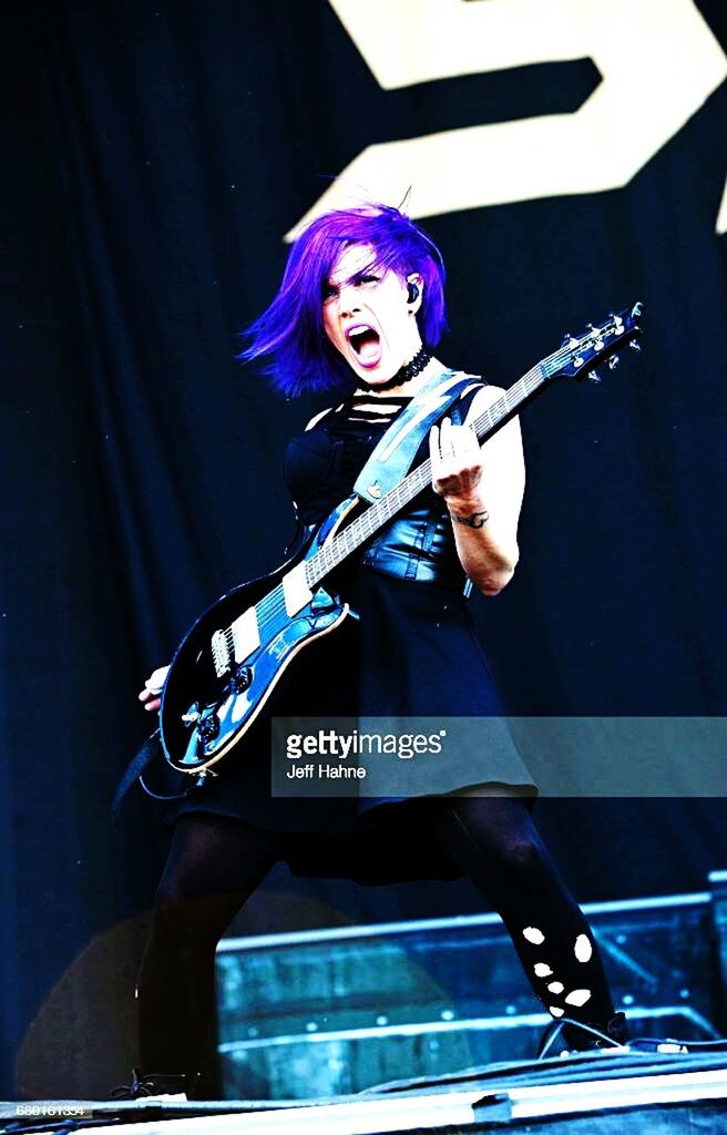 PORTRAIT OF YOUNG WOMAN WEARING GUITAR