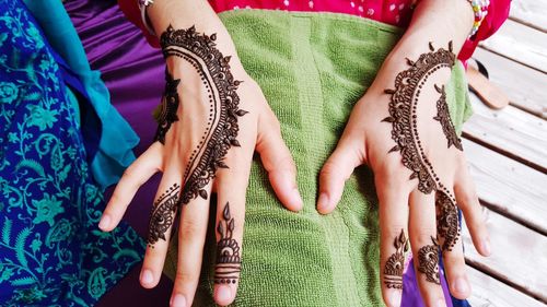 Midsection of woman with henna tattoo on hand