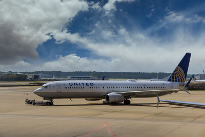 Airplane on airport runway against sky