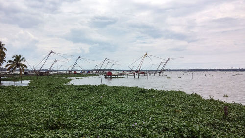 Cranes in amusement park against sky