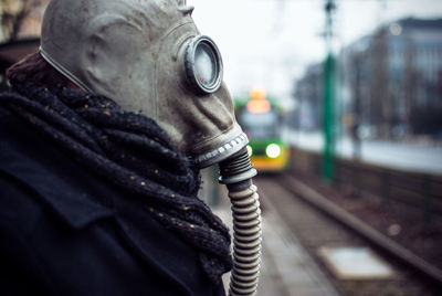 Side view of man wearing gas mask while standing at railroad station platform