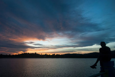 Silhouette people standing by lake against sky during sunset