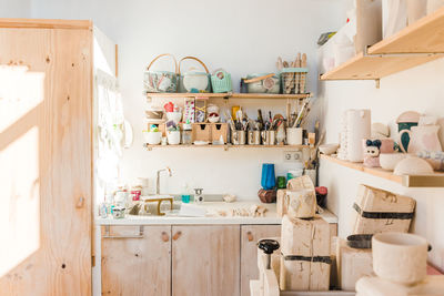 Studio with wooden shelves with different instruments for pottery and utensil near sink in daylight