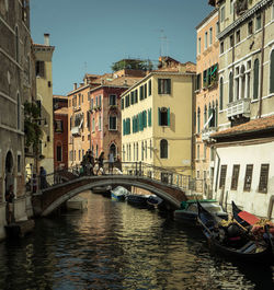 Bridge over canal amidst buildings in city against clear sky venice italy