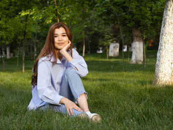 Portrait of young woman sitting on field