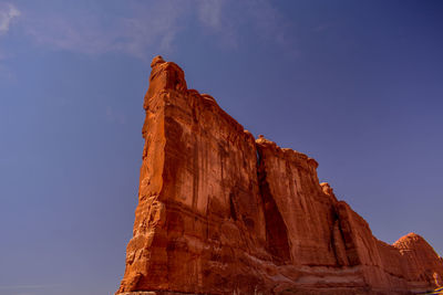 Low angle view of rocky mountain against blue sky