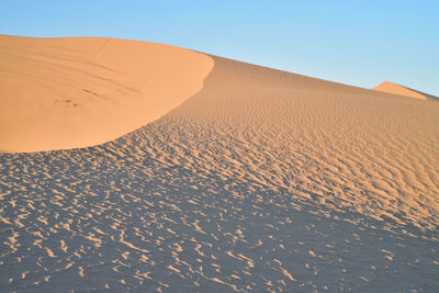 Sand dunes in desert against clear sky