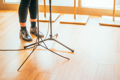 Low section of woman standing by tripods on hardwood floor
