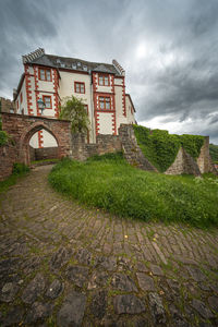 Footpath by old building against sky