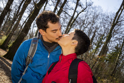 The young couple is kissing while hiking in the woods. 
