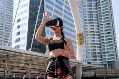 Low angle view of woman using virtual reality simulator in city