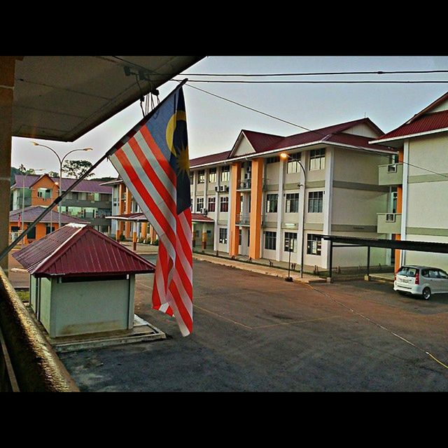 architecture, building exterior, built structure, window, residential structure, residential building, house, city, building, sunlight, day, sky, street, no people, outdoors, balcony, shadow, clear sky, flag, red