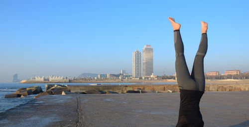 Man standing by sea in city against clear sky