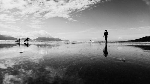 Silhouette people playing on beach against sky