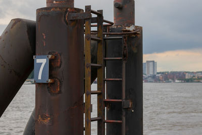 Close-up of rusty metal structure in sea against sky