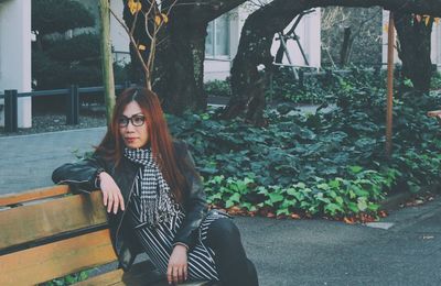 Thoughtful woman sitting on bench at sidewalk