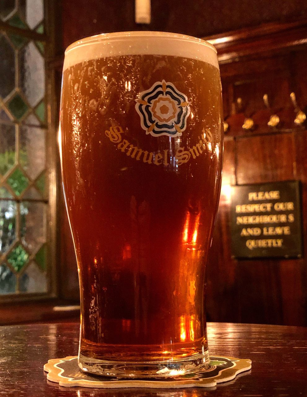 CLOSE-UP OF BEER GLASS ON TABLE AT BAR