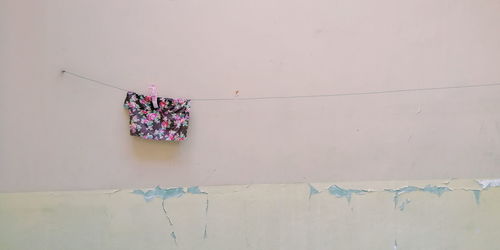 Low angle view of clothes drying on clothesline against white wall