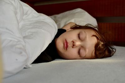 Close-up of cute boy sleeping on bed at home