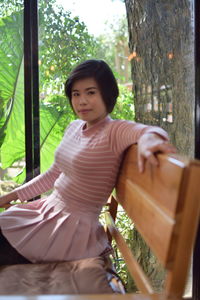 Portrait of young woman sitting on tree trunk