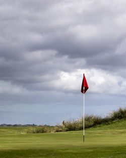 Red flag on golf course against sky