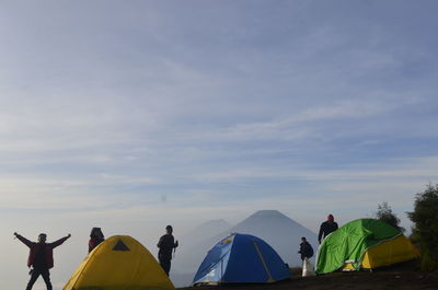 Rear view of people standing on mountain against sky