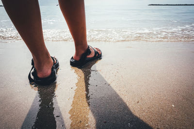 Low section of woman standing at beach