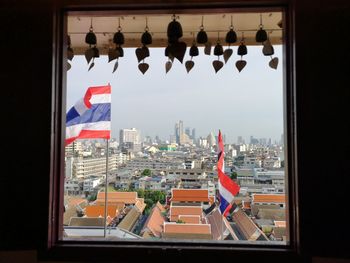 Buildings against sky seen through window