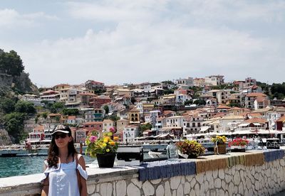 Woman standing by buildings in city against sky