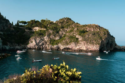 Aerial view of taormina, sicily in italy. tree covered hills and and water of bay with boats