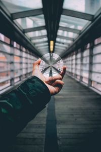 Close-up of man holding glass while standing on footbridge