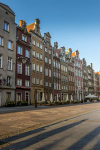 Buildings by street against blue sky