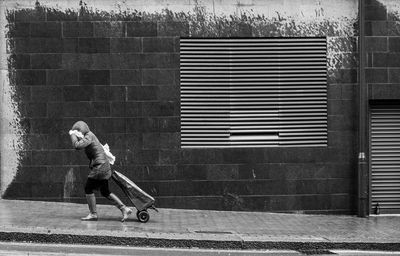 Full length of woman on footpath against wall