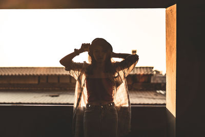 Woman standing against built structure against clear sky