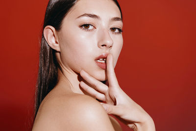 Close-up of young woman against yellow background