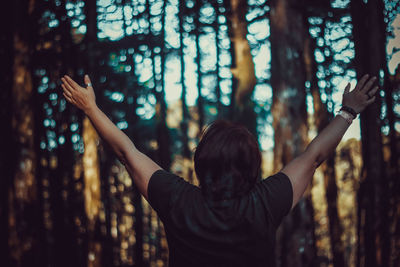 Rear view of woman standing in forest