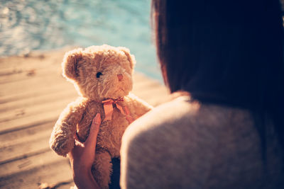 Close-up of woman holding teddy bear at lake