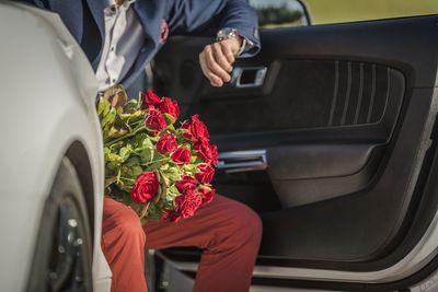 Midsection of man holding bouquet while sitting in car